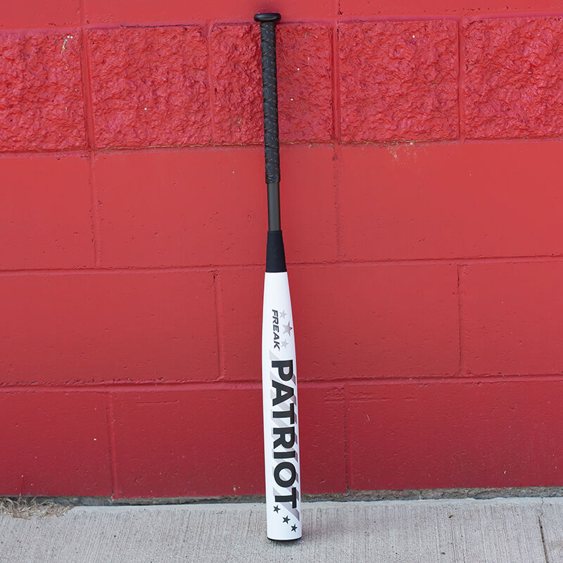 A white/black Miken Freak Patriot bat leaning against a red wall - SKU: MSA3FPL loading=