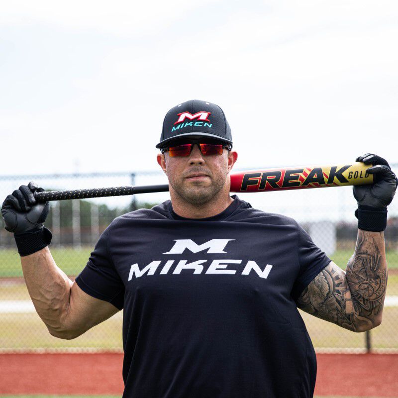 Josh Riley holding a Freak Gold USSSA bat on his neck behind his head